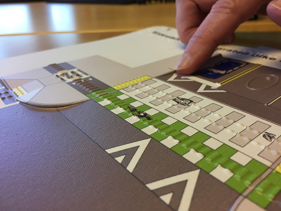 A person with vision disability uses a tactile map to explore a street design concept using touch.