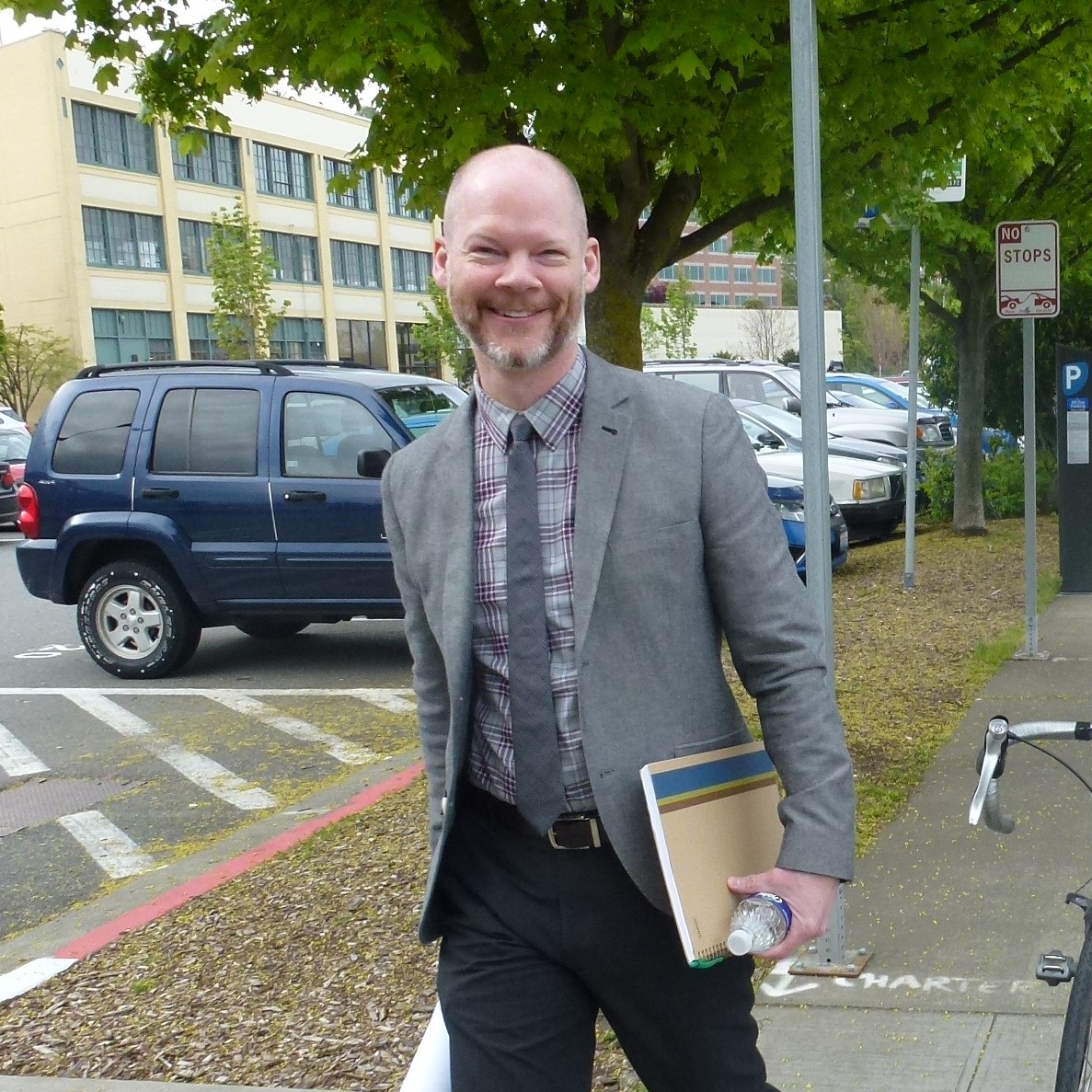 Kenneth Loen walks toward a public meeting with plans for a project in hand
