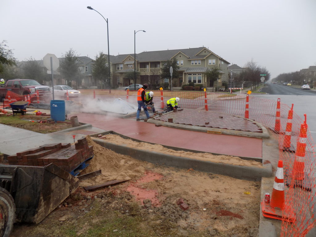 Crews work on constructing new protected intersection elements at the intersection of Zach Scott Street and Berkman Dr. where two bikeways connect in Austin, TX.