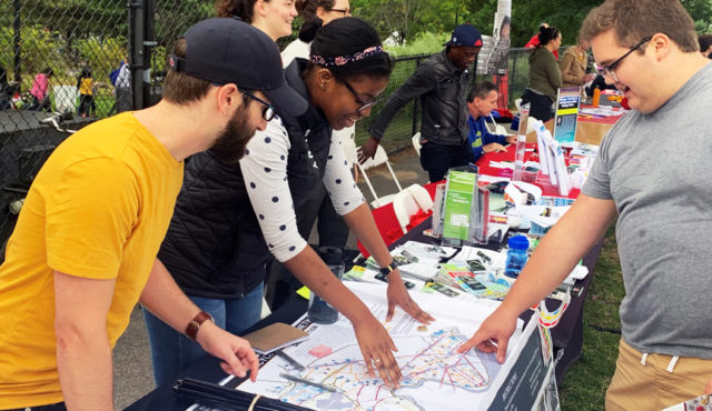 A group of people outside stand over a table pointing to a map of Cambridge