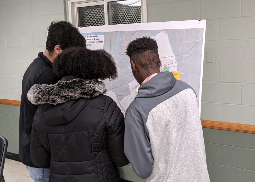 Three teenagers looking at a design board during a public engagement meeting in Painesville, OH.
