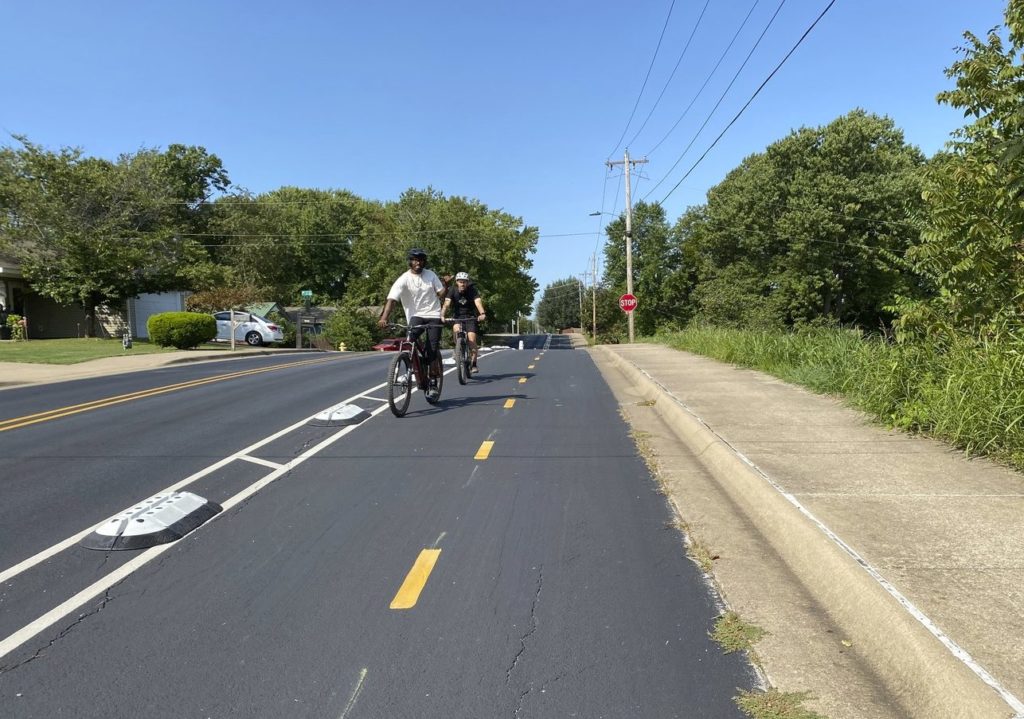 Man bicycling toward camera on 2 way bike lane on a suburban road.