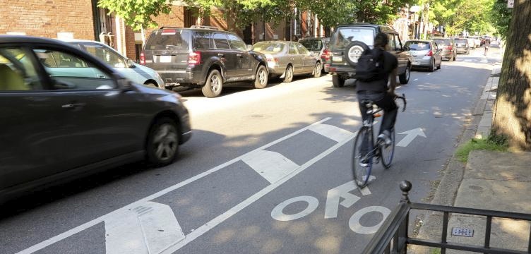 A cyclist riding in the buffered bike lane alongside vehicle in Philadelphia, PA.