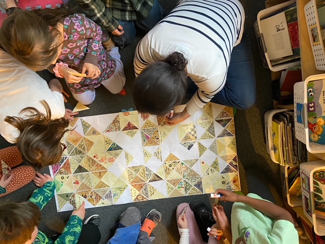 An overhead photo of a group of elementary-age students adding suggestions to a transportation safety quilt.